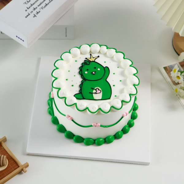 Bánh kem khủng long trên mặt bánh với đường viền xanh, trắng nổi bật