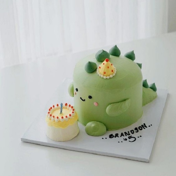 Bánh kem tròn đơn giản với hình khủng long xanh lá nhỏ nhắn.