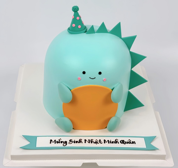 Bánh sinh nhật hình khủng long nhỏ dễ thương trên nền kem xanh dương.