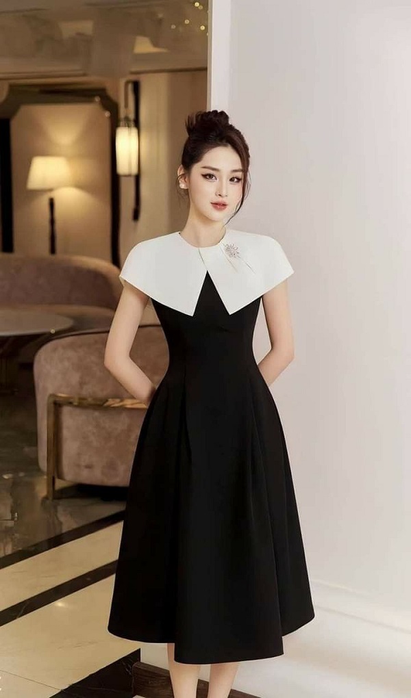 Đầm đen dáng xòe nhẹ nhàng, phần cổ trắng tinh tế tạo điểm nhấn, mang đến vẻ đẹp thanh lịch và nữ tính.