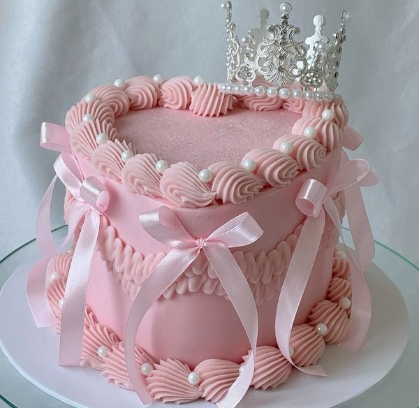 Bánh kem trái tim màu hồng nhạt kết hợp nơ lụa và vương miện xinh xắn