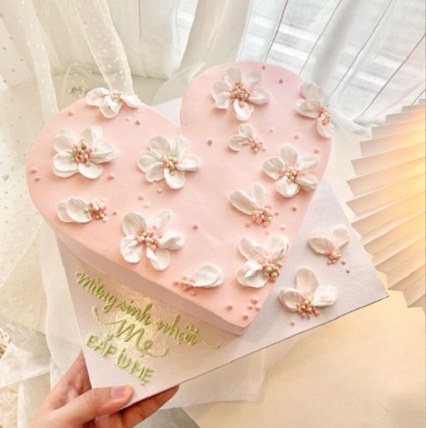 Bánh kem trái tim màu hồng trang trí bằng hoa kem ngọt ngào